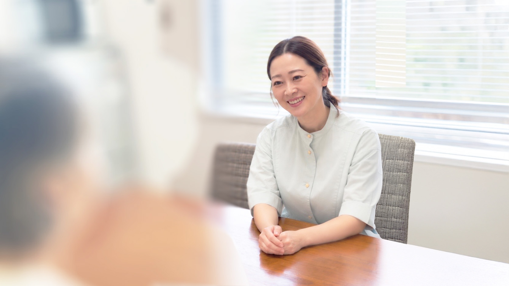 自然光の入る明るい相談室で静かに過ごす人物の後ろ姿